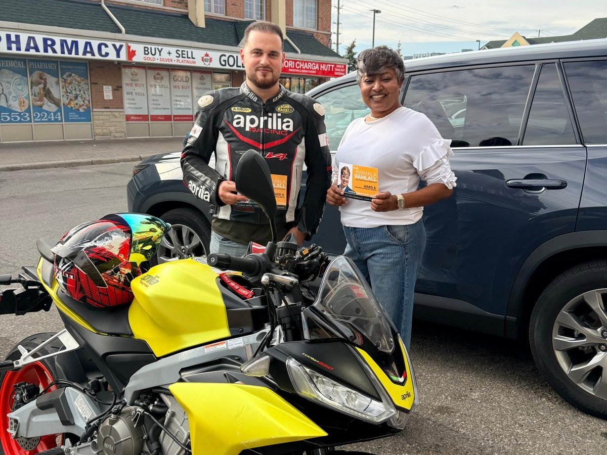 Nirmala Ramlall talking with a Ward 4 resident beside his motorcycle